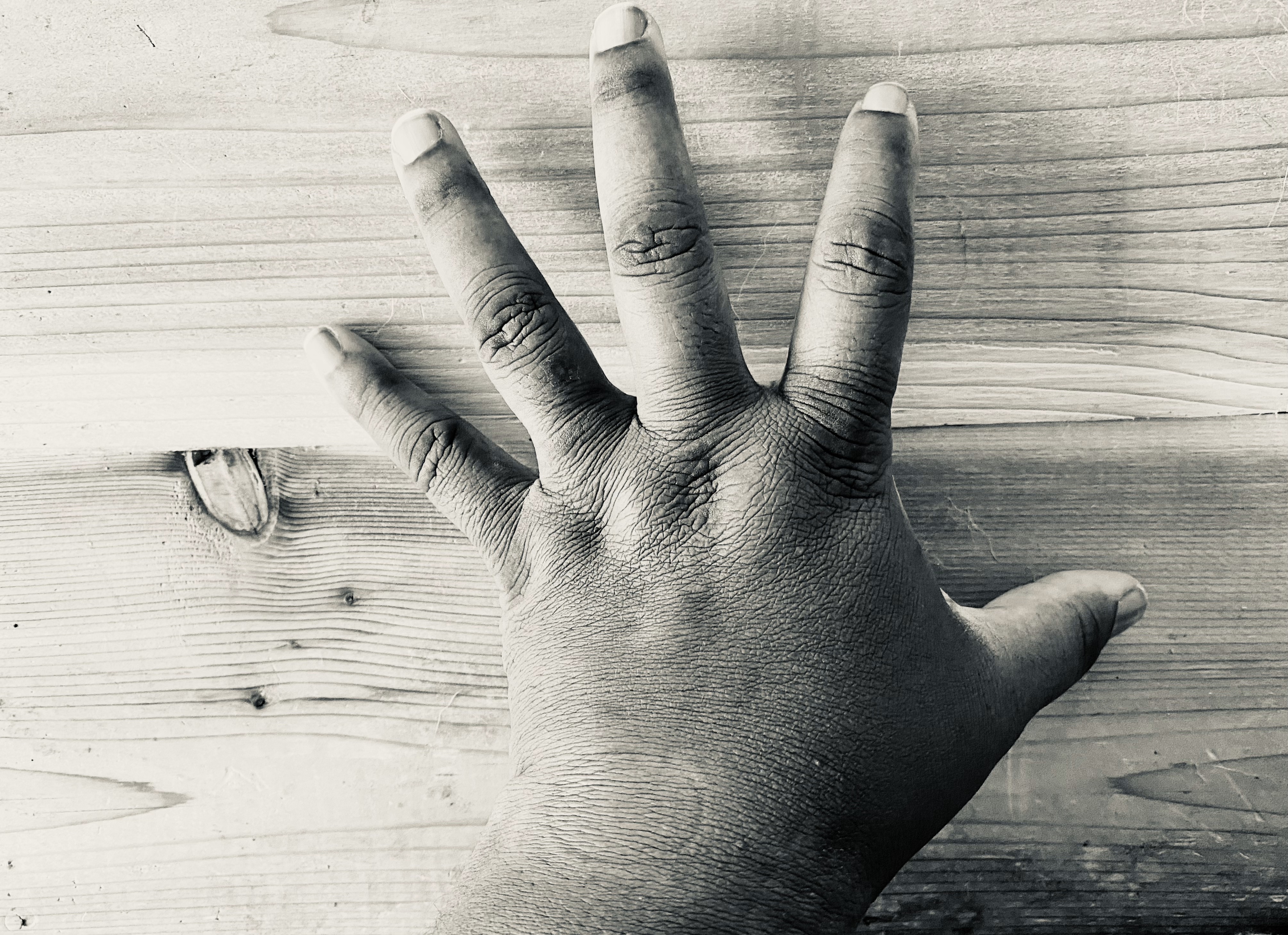 Close image of a black person's hand with a board in the background. 